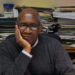 Dr. Willie Tolliver sits at a desk with books and DVDs surrounding him.
