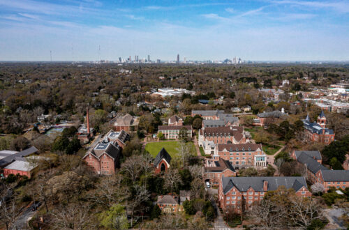 aerial shot shows the many brick buildings of Agnes Scott College with Atlanta sitting under the blue sky in the horizon