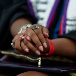The hands of a graduate are clasped. Their black onyx ring featured in view.