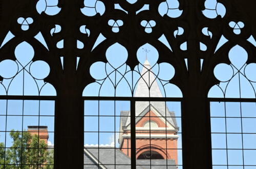 A building is seen through a large gothic window.