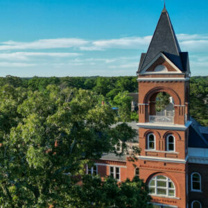 a drone photo of a historic building rises up among a crop of trees