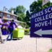 Two people move a box by a purple Agnes Scott College Move-In directional sign.