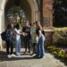 a group of students gather in front of a decorative brick arch