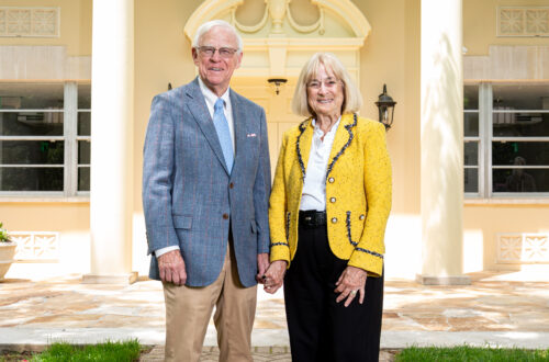 A couple stand in front of a well lit building.